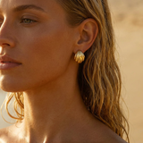 Close-up of a woman wearing gold earrings with a blurred background