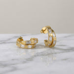 Gold hoop earrings on a wet marble surface