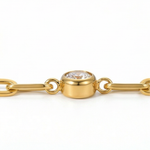 Close up of white gemstone on a gold chain bracelet on a white background