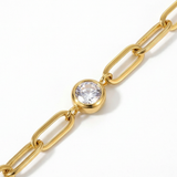 Close up of white gemstone on a gold chain bracelet on a white background