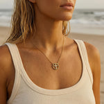 A woman wearing a gold cross necklace with rhinestones at the beach