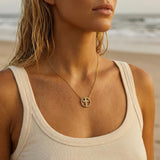 A woman wearing a gold cross necklace with rhinestones at the beach
