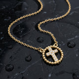 Gold cross necklace with rhinestones on a wet black marble surface