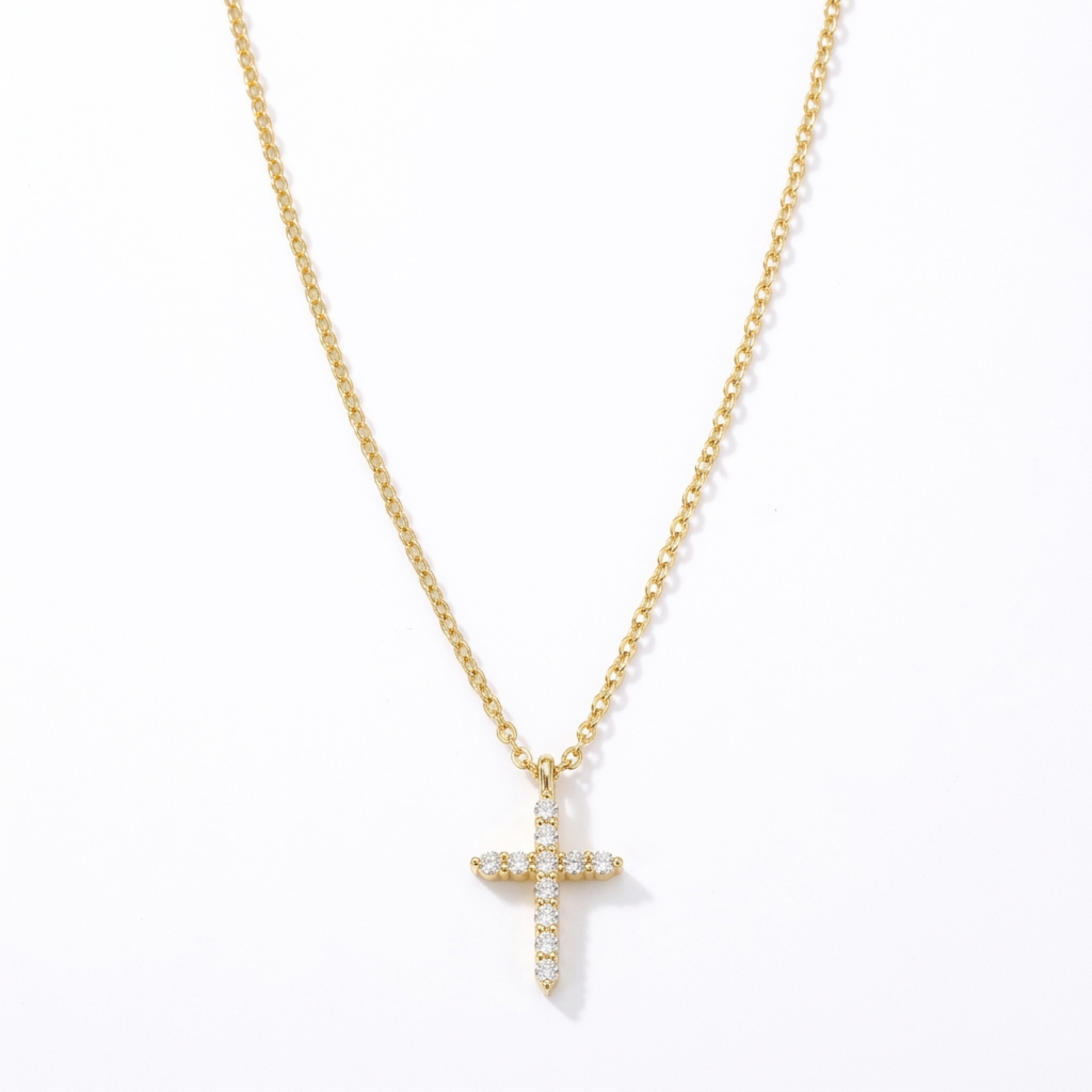 The Glory'd Signature Cross Necklace which is a yellow gold cross pendant necklace adorned with clear round-cut gemstones, suspended from a matching gold chain against a plain white background.