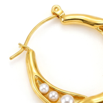 Close up of gold hoop earring with pearls on a white background