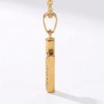 Side view of gold cross pendant necklace on a white background