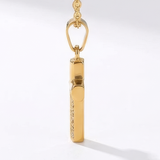 Side view of gold cross pendant necklace on a white background