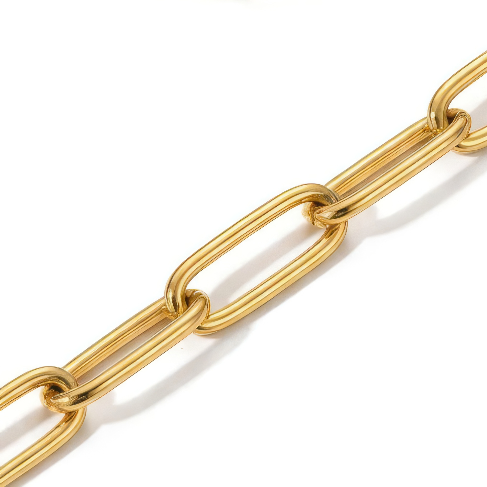 Close-up of the links of a gold paperclip chain bracelet on a white background