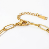 Close-up of the clasp of gold paperclip chain bracelet on a white background