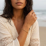 Woman wearing a gold paperclip chain bracelet on her wrist at the ocean