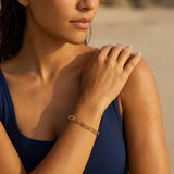Woman wearing gold paperclip chain bracelet at the beach