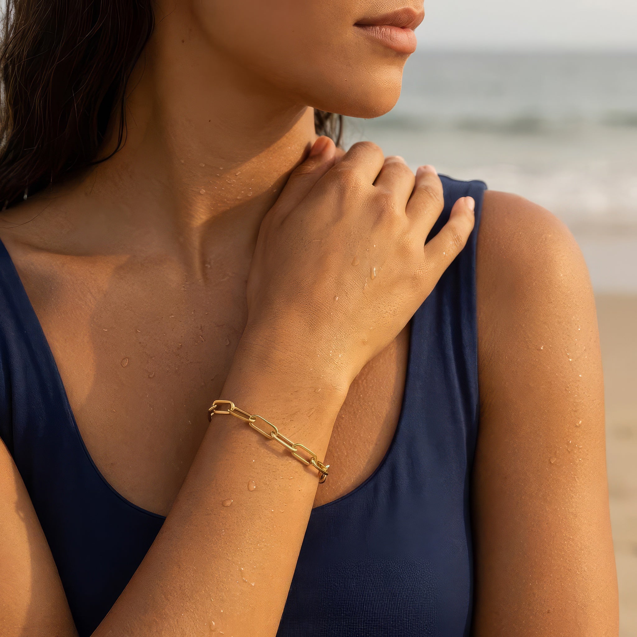 Woman wearing gold paperclip chain bracelet at the beach